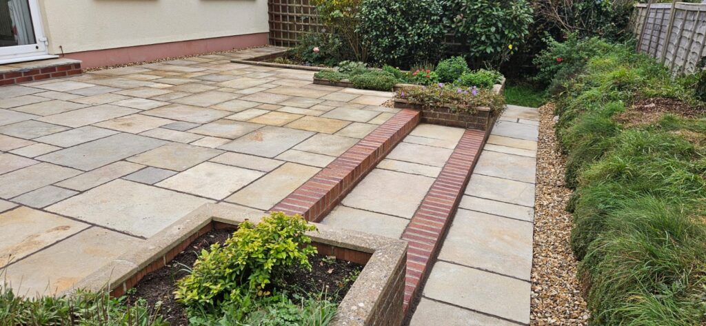 beige paving in back garden with red brick edging