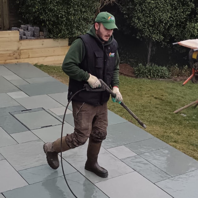 Sam pressure washing a slate patio as part of a garden maintenance package.